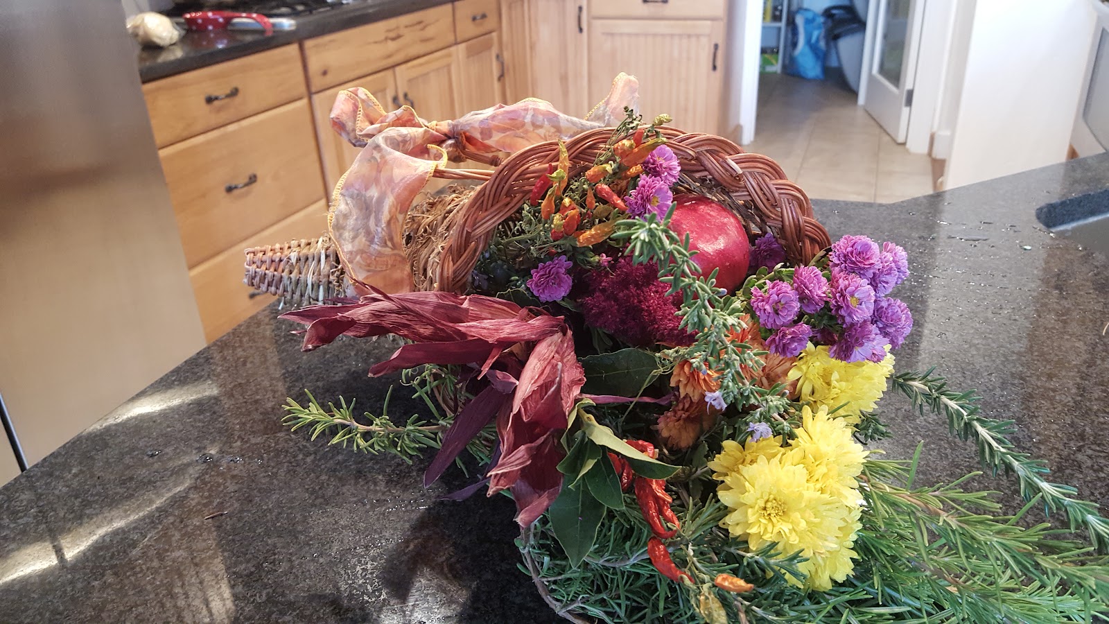 A harvest basket from Lindsay Organic Farm holding chrysanthemums, amaranth, rosemary, hot peppers and a pomegranate